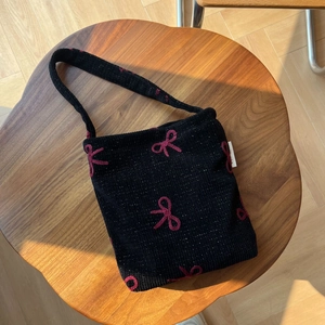 Gros plan d'un sac cabas en maille noire avec nœud rouge crocheté sur bois