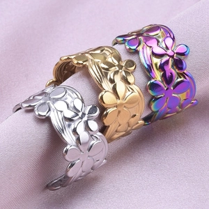 Detailed close-up of three floral steel rings in silver, gold, and rainbow on satin fabric