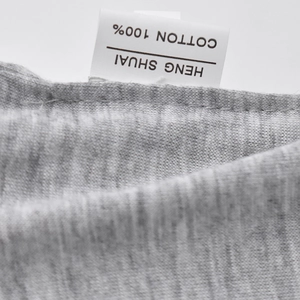 Détail de l'étiquette 100% coton et de la texture en tricot gris doux du bonnet