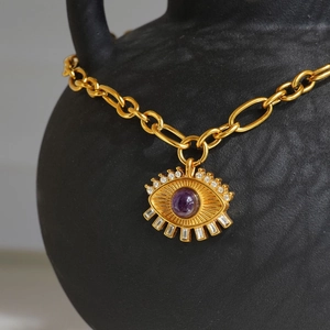 18k gold plated evil eye necklace with purple zircon pendant on a textured black jar