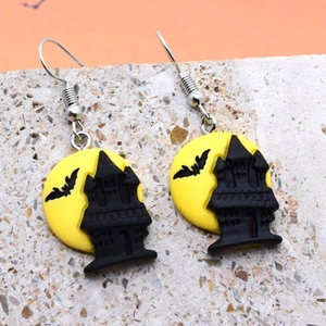Detail of Halloween resin earrings featuring a yellow moon, castle, and bat on metal hooks
