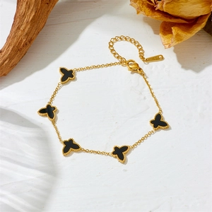 Macro shot of gold-plated stainless steel bracelet with black four-leaf clover charms