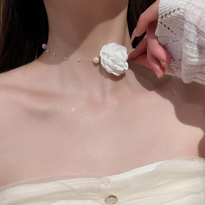Gros plan d'un collier vintage français avec fleur en tissu blanc et perles élégantes