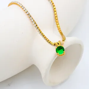 Detailed view of gold necklace with square zircons and large round green gemstone pendant
