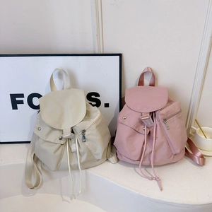 Detail of minimalist nylon backpacks in beige and pink showing drawstrings and front pockets