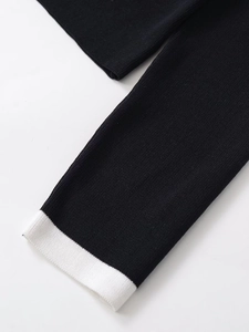 Close-up of black knit cardigan featuring contrasting white ribbed cuffs and soft texture