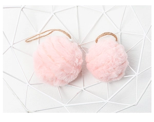 Close-up of two pink fuzzy felt pompom ornaments with brown string in a white basket