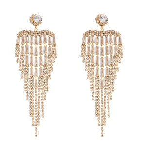 Boucles d'oreilles pendantes dorées de luxe avec strass et franges en cristal sur fond blanc