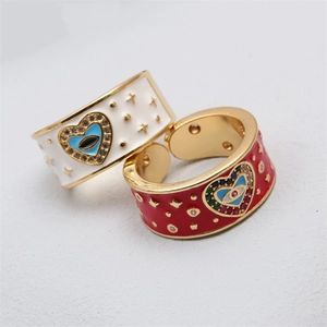 Detail view of heart-shaped evil eye rings with red and white enamel on a white surface