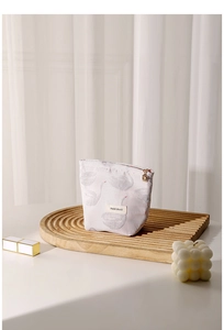 Detail of light pink swan jacquard makeup bag with gold zipper on wooden tray