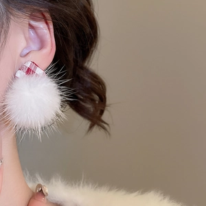 Close-up of model wearing white plush ball and red checkered fabric heart stud earrings