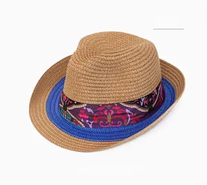 Close-up of khaki straw hat featuring ethnic purple pattern ribbon and navy woven trim