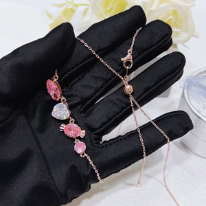 Close-up of rose gold bracelet with pink heart and candy-shaped stones held in black glove