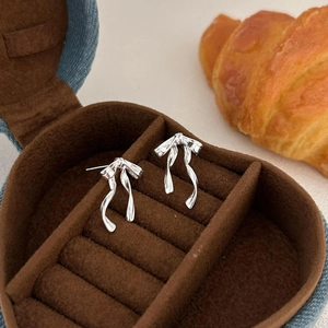 Minimalist 925 sterling silver bow knot stud earrings in a heart-shaped jewelry box