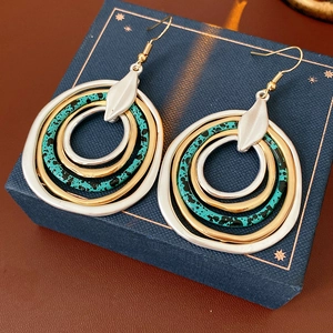 Detail of bohemian layered hoop earrings with turquoise, gold and silver rings on a blue box