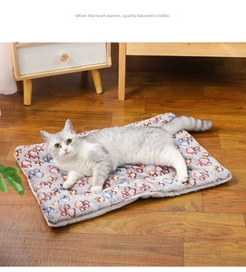 Close-up of thick plush pet mat with colorful paw prints and silver tabby cat sleeping
