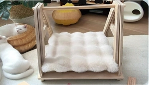 Detail of wooden cat bed structure with plush white cushion in a cozy home setting