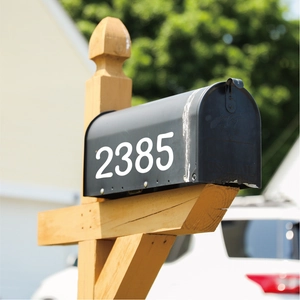 Detail of 4-inch white waterproof adhesive numbers 2385 on a black outdoor mailbox