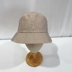 Detailed close-up of sparkling silver rhinestones on a beige cotton bucket hat surface