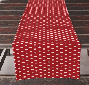 Detailed view of red cotton linen table runner with white polka dot pattern on wood surface