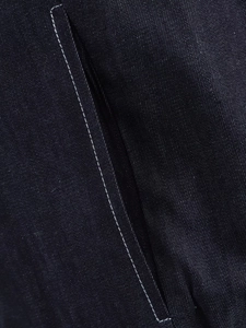 Close-up detail of dark blue denim fabric with white contrast stitching on a pocket