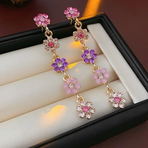 Close-up of long tassel flower earrings with pink and purple rhinestones in a gift box