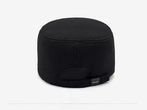 Rear detail of black wool flat cap showing thick thermal fabric and brand label