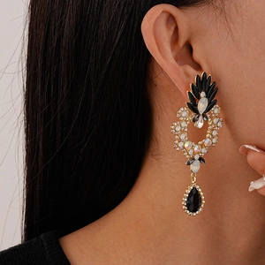 Close-up of vintage flower drop earrings with black water-drop stone on a model