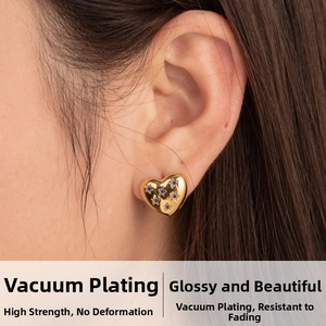 Detail of golden heart-shaped stud earring with blue stars on model's ear