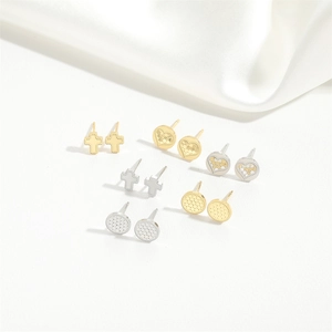 Flat lay of vintage cross, heart, and round stud earrings set with white silk detail