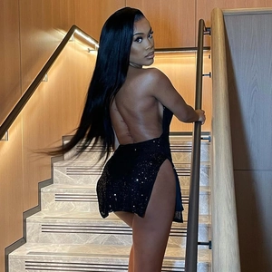 Close-up of a sexy black sequin backless dress with a high slit on wooden stairs