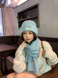 Detail of light blue knit hat and scarf set with cute dog embroidery and red lettering
