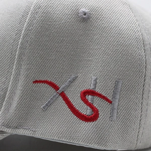Detailed close-up of XSH letter embroidery on high-density grey cotton baseball cap