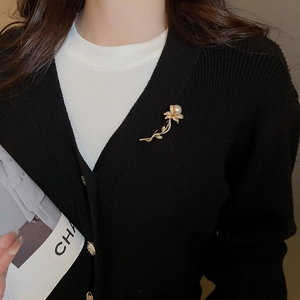 Detailed close-up of a gold floral brooch with pearl and sparkling crystals on clothing
