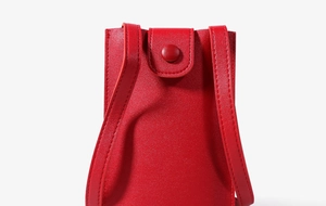 Detail of red leather mini crossbody phone bag showing fine grain and snap button closure
