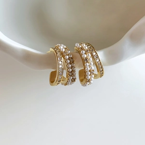 Detail of 14k gold plated C-shaped earrings with pearls and pavé cubic zirconia