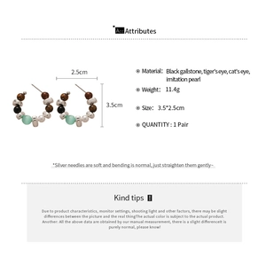 Detail view of multi-material earrings with tiger eye, opal, and pearls on white background