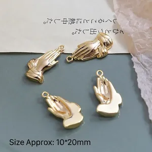 Macro shot of gold-plated praying hands charms for DIY jewelry making 10x20mm