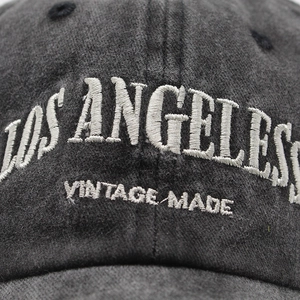 Detailed close-up of white 3D embroidery on vintage charcoal washed cotton baseball cap