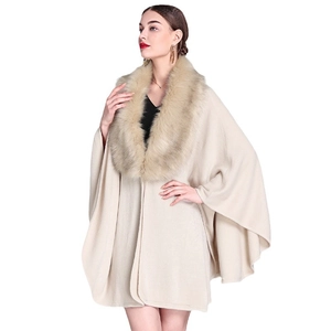 Elegant beige knit poncho with faux fox fur collar for women in a professional studio shot