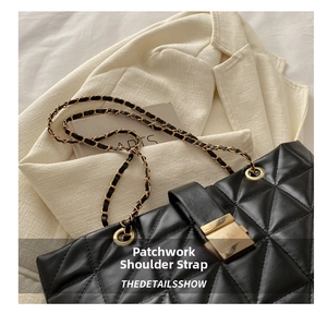 Detail of quilted black leather tote with gold metal buckle and chain strap