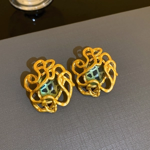 Detailaufnahme von goldenen Vintage Barock Ohrringen mit strukturiertem grünem Stein.