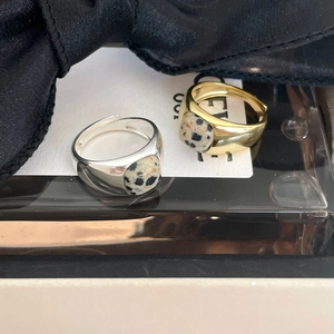 Detailed view of silver and gold marble stone rings on elegant dark glass and white card