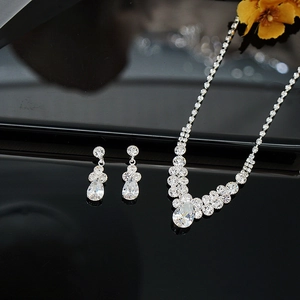 Elegant silver teardrop necklace and earring set with cubic zirconia on reflective background