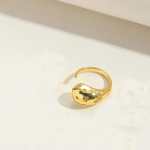 Macro detail of gold stream-lined ring with sparkling gemstones on a beige background