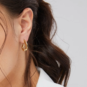 Minimalist gold egg-shaped geometric earrings with a twisted metallic punk design on model