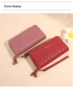 Pink and red long quilted wallets with wrist straps and double zippers in scene display
