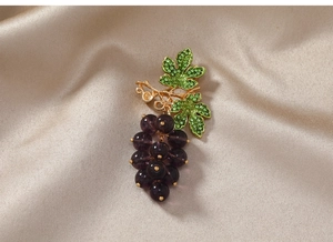 Macro view of purple grape cluster brooch with green rhinestone leaves and gold plating
