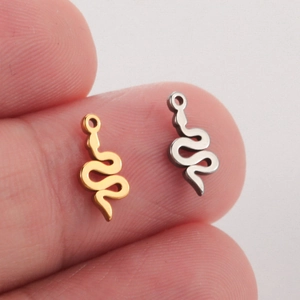 Polished gold and silver snake charms for DIY jewelry held on fingertips for size