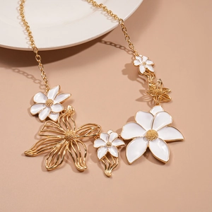 Detail of gold necklace with white enamel flowers and hollow metallic floral pendants